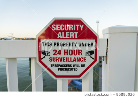 Security Alert This Property Under 24 Hour Surveillance sign on a railings at Destin, Florida 96893026