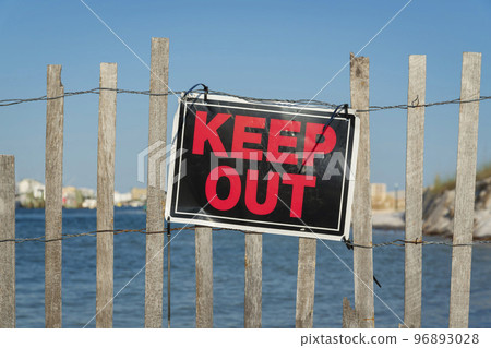 Red and black Keep Out sign on a wire and wood slat fence at Destin, Florida 96893028