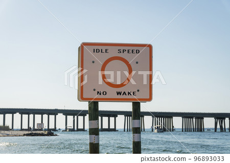 Idle Speed No Wake Sign in a waterway below the bridge at Destin, Florida Idle Speed No Wake Sign in a waterway below the bridge at Destin, Florida 96893033