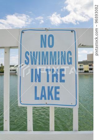 Signage on a white railings with No Swimming in the Lake at Destin, FL 96893082