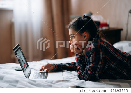 Young woman work while with laptop lying on bed Young woman work while with laptop lying on bed 96893563