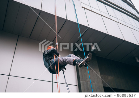 Industrial climber in uniform and helmet rises 96893637