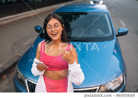 Woman using mobile phone near car at the street 96893689