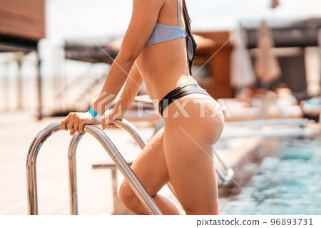 Cropped photo. Young woman climbs the ladder out swimming pool 96893731