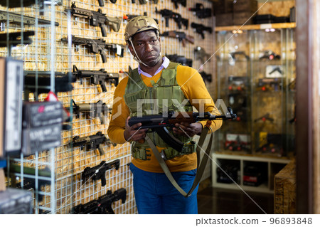 Man in armor choosing weapon in arms shop 96893848