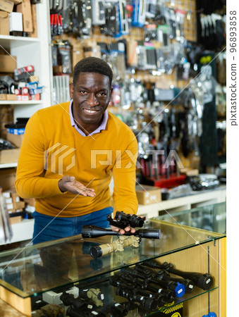 Salesman in arms shop presenting rifle telescope 96893858