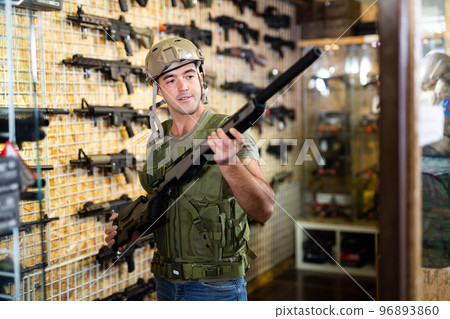 Man choosing rifle in airsoft shop 96893860