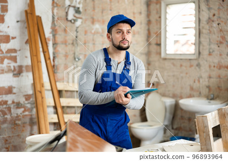 Foreman making task list during works in building under construction Foreman making task list during works in building under construction 96893964