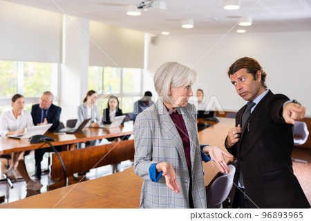 Middle aged white dark-haired male manager dismissing senior white female employee Middle aged white dark-haired male manager dismissing senior white female employee 96893965