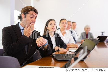 Sleepy businessman yawning during conference Sleepy businessman yawning during conference 96893977