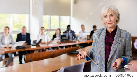 Senior businesswoman gesturing and explaining in meeting room Senior businesswoman gesturing and explaining in meeting room 96894003