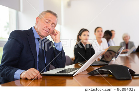 Mature businessman fell asleep at a business meeting in negotiation room Mature businessman fell asleep at a business meeting in negotiation room 96894022