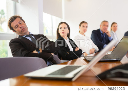Mid-aged white business man having a nap during a meeting Mid-aged white business man having a nap during a meeting 96894023
