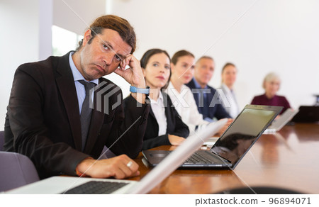 Middle aged white business man yawning at boring meeting 96894071