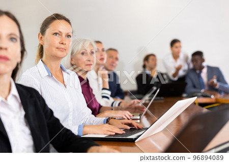 Middle aged white businesswoman sitting at meeting and listening to presentation Middle aged white businesswoman sitting at meeting and listening to presentation 96894089