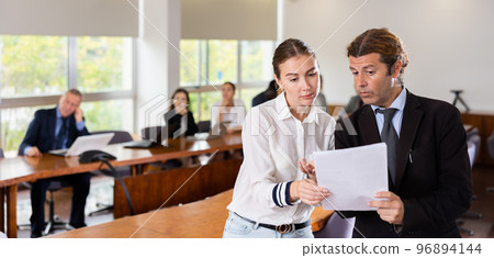 Secretary and employer discussing documentation during business meeting 96894144