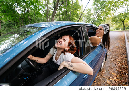 Two girlfriends fool around and laughing together in a car 96894229