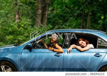 Two girlfriends fool around and laughing together in a car Two girlfriends fool around and laughing together in a car 96894233