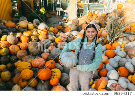 Female farmer holding pumpkin on the background of autumn harvest. Female farmer holding pumpkin on the background of autumn harvest. 96894317