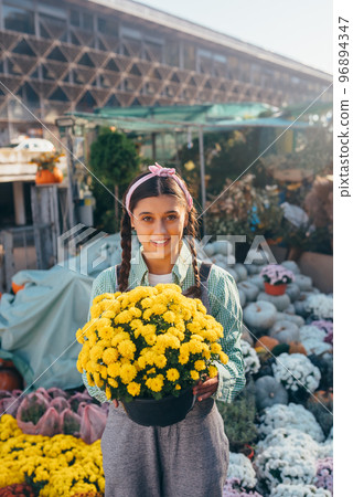 Woman holding decorative flower in flower pot on the market. 96894347