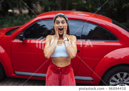 Portrait of pretty Caucasian woman standing against new red car Portrait of pretty Caucasian woman standing against new red car 96894438