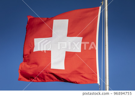 Swiss flag winding with blue sky in the background, Swiss Alps 96894755