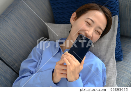 Woman smiling while looking at smartphone Woman smiling while looking at smartphone 96895655
