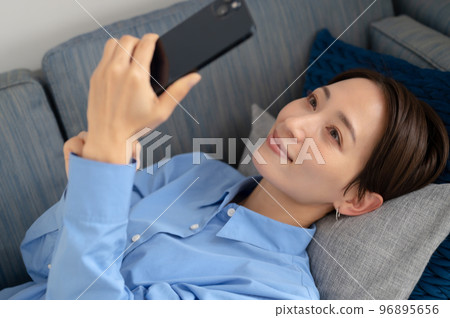 Woman smiling while looking at smartphone Woman smiling while looking at smartphone 96895656