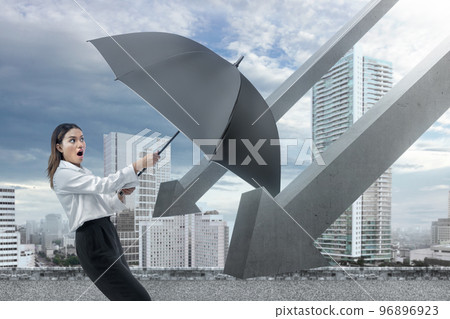 Asian businesswoman tries to hold back a falling arrow with a black umbrella Asian businesswoman tries to hold back a falling arrow with a black umbrella 96896923