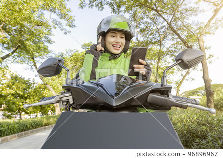Asian woman works as a motorcycle taxi driver checking order on her mobile phone 96896967