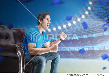 Asian man sitting on the couch with an excited expression Asian man sitting on the couch with an excited expression 96897570