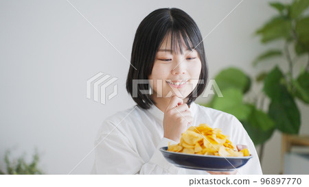 A woman who eats potato chips (unhealthy diet).. 96897770