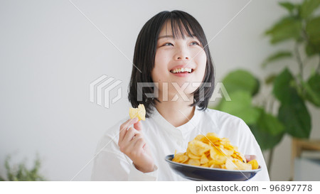 A woman who eats potato chips (unhealthy diet).. 96897778