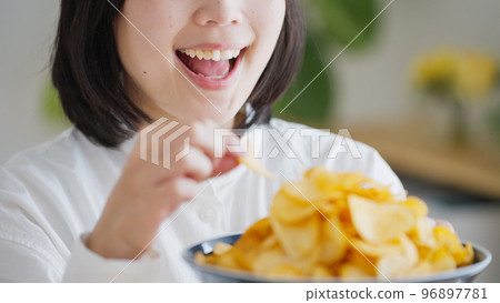 A woman who eats potato chips (unhealthy diet).. 96897781