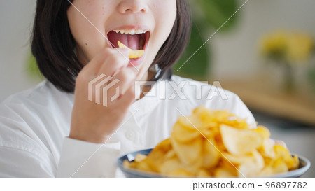 A woman who eats potato chips (unhealthy diet).. 96897782