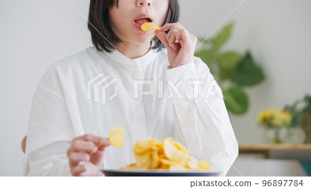 A woman who eats potato chips (unhealthy diet).. 96897784