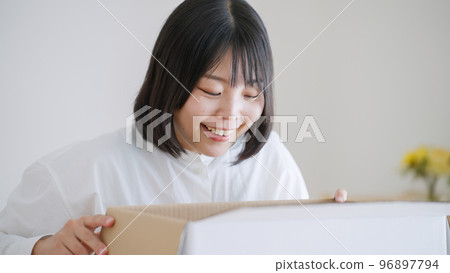 A woman who opens a cardboard (moving/packing) 96897794