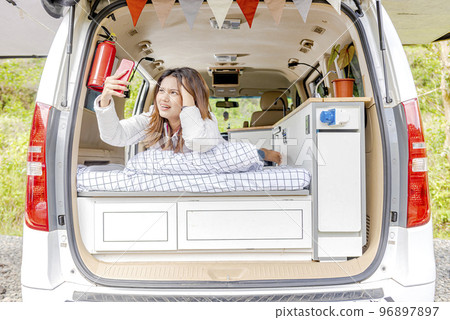 Asian woman searching the signal for her mobile phone inside the campervan Asian woman searching the signal for her mobile phone inside the campervan 96897897