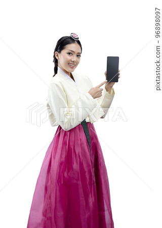 Asian woman wearing a traditional Korean national costume, Hanbok, standing while showing empty screen on mobile phone Asian woman wearing a traditional Korean national costume, Hanbok, standing while showing empty screen on mobile phone 96898097