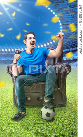 Asian man with the ball sitting on the couch with an excited expression 96898164