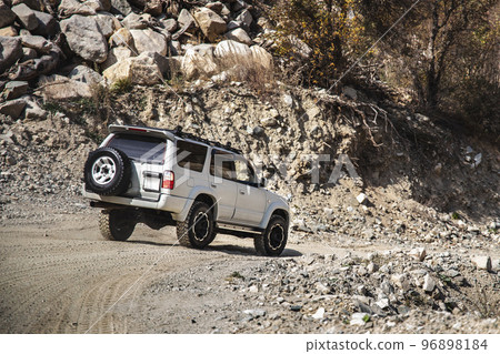 White SUV going down the mountainous rocky terrain 96898184
