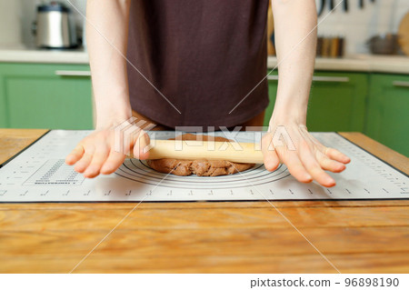 Rolling out cookie dough on a silicone baking mat on a wooden table with copy space 96898190