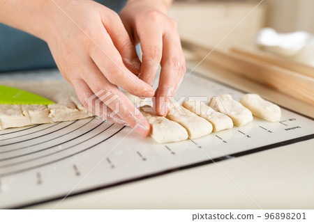Close-up on the hands of a cook laying out pieces of dough. Perfectionism in the process of cooking 96898201