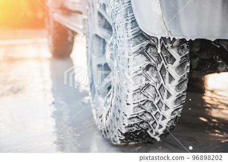 Close-up of the front of a car wheel with soap suds, car body cleaning chemicals 96898202