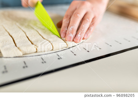 Close-up of cutting the rolled dough into equal parts according to the markup, copy space 96898205