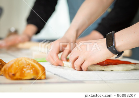 Close-up on cooks hands, cooking bakery in a bright kitchen by two chefs, selective soft focus 96898207