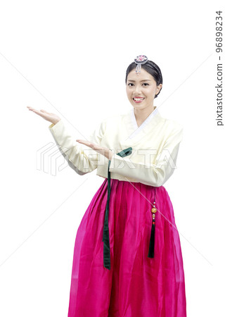 Asian woman wearing a traditional Korean national costume, Hanbok, standing with an open palms and showing something 96898234