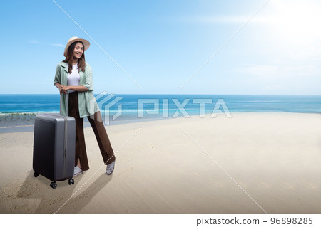 Asian woman with a hat and suitcase standing on the beach Asian woman with a hat and suitcase standing on the beach 96898285