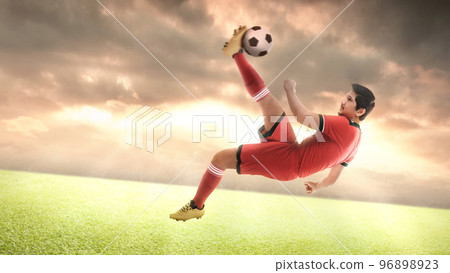 Asian football player man in a red jersey kicking the ball Asian football player man in a red jersey kicking the ball 96898923