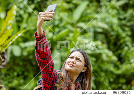 Asian woman with a backpack searching the signal for her mobile phone 96899025